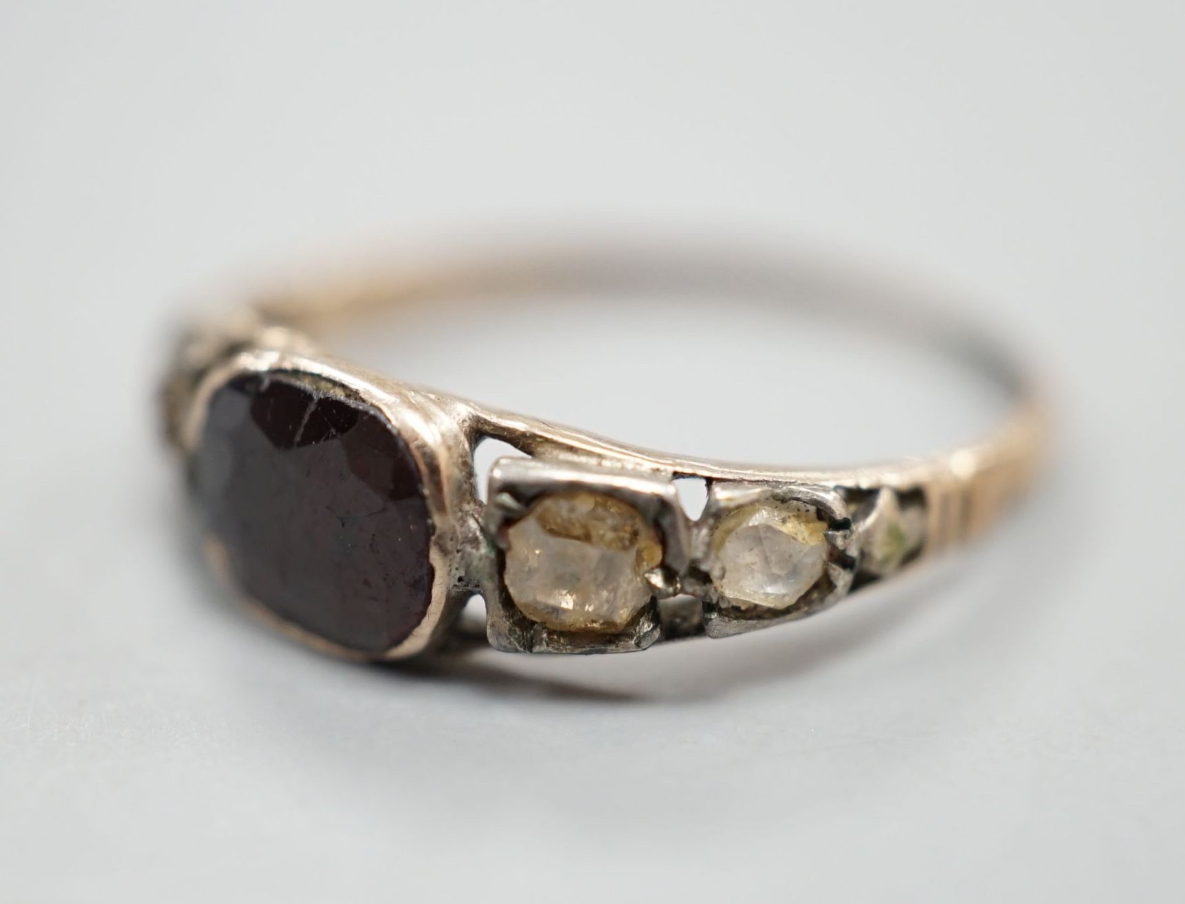 A 19th century yellow metal, garnet and diamond set five stone half hoop ring, size M, gross weight 1.7 grams.